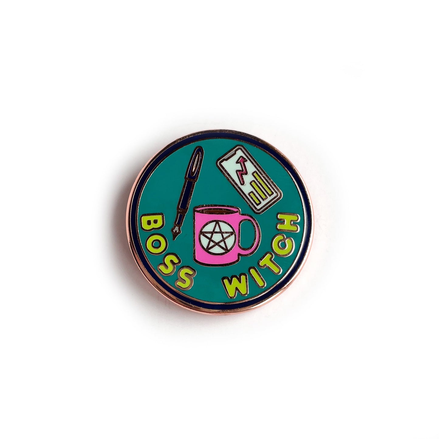 A circular enamel pin with copper details. It has a purple border with a turquoise background with lime green letters that read "Boss Witch". There is also a hot pink coffee cup with a pentacle, a purple fountain pen, and a phone with a graph on it.