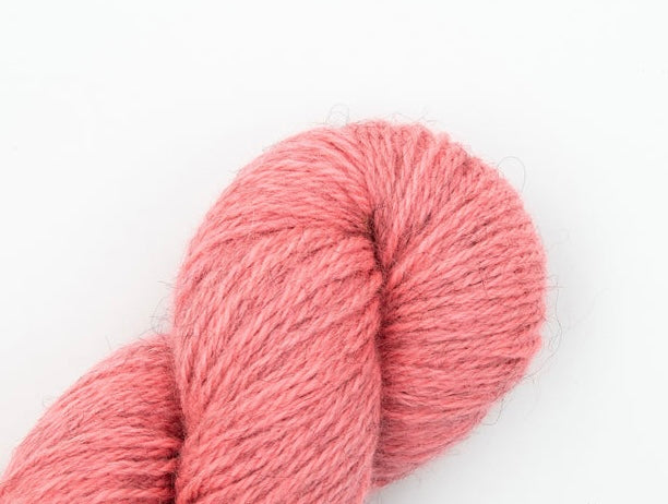An image of a skein of worsted weight yarn in a heathered light pink color against a white background.