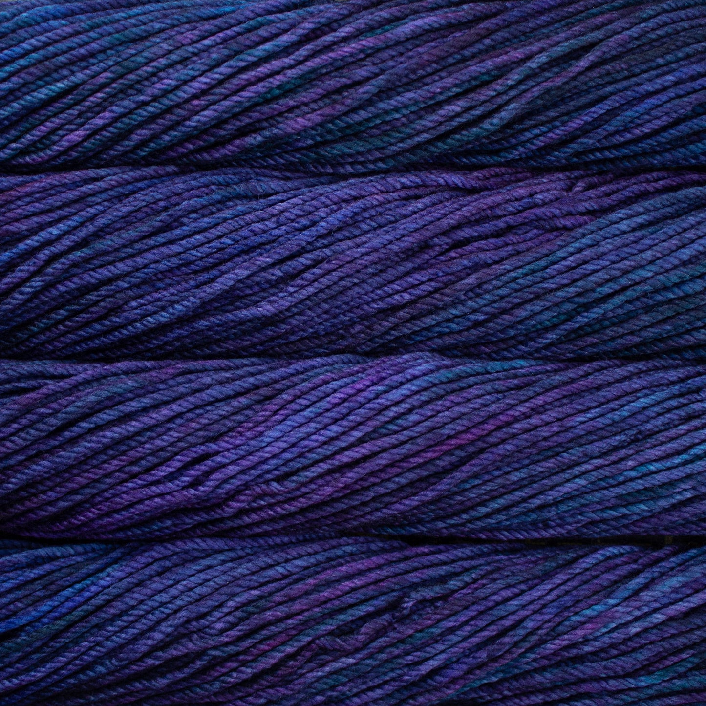 A close up image of skeins of Malabrigo Chunky bulky weight yarn in deep purple and navy blue shades.