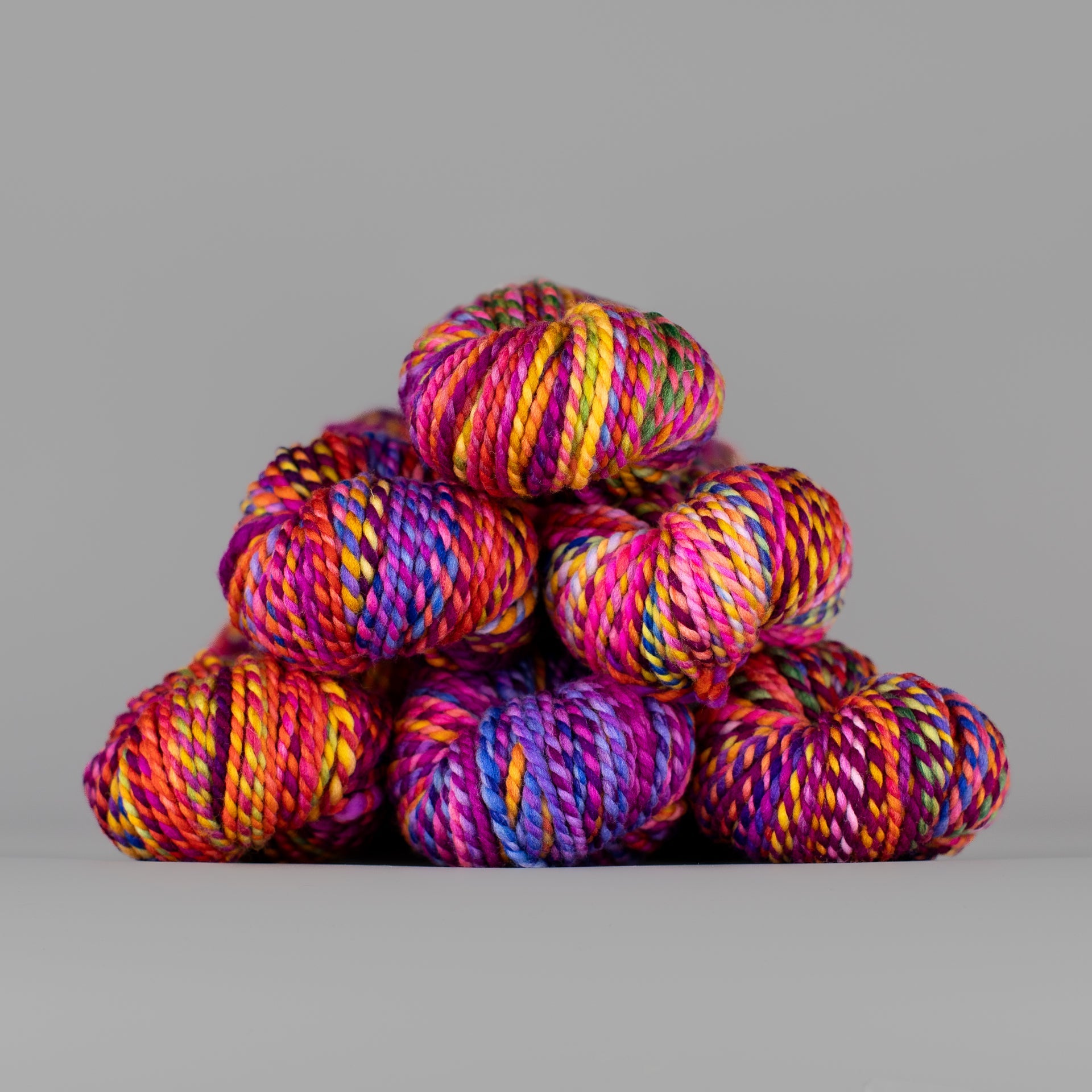 Skeins of Spincycle Plump Bulky weight yarn in red, orange, pink, blue, purple, and yellow color gradient
