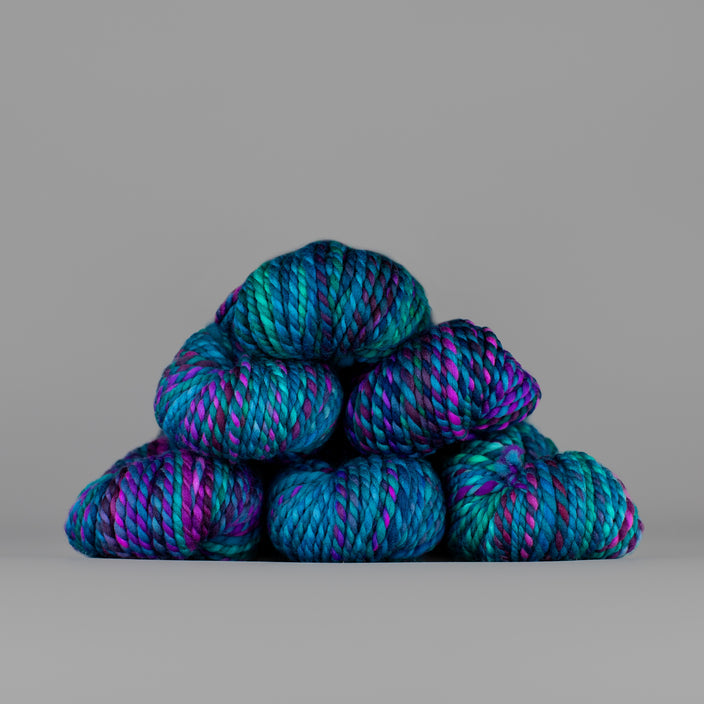 Skeins of Spincycle Plump Bulky weight yarn in aqua blue, teal green, and purple color gradient