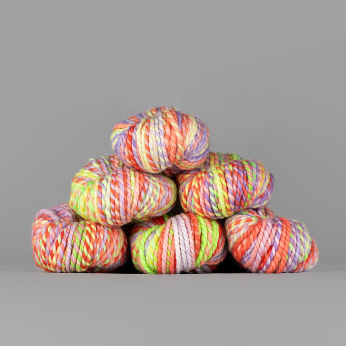 Skeins of Spincycle Plump Bulky weight yarn in pink, orange, yellow, and purple color gradient