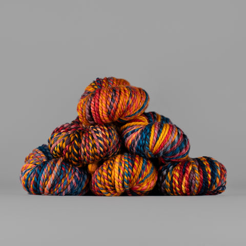 Skeins of Spincycle Plump Bulky weight yarn in yellow, orange, blue, and black color gradient