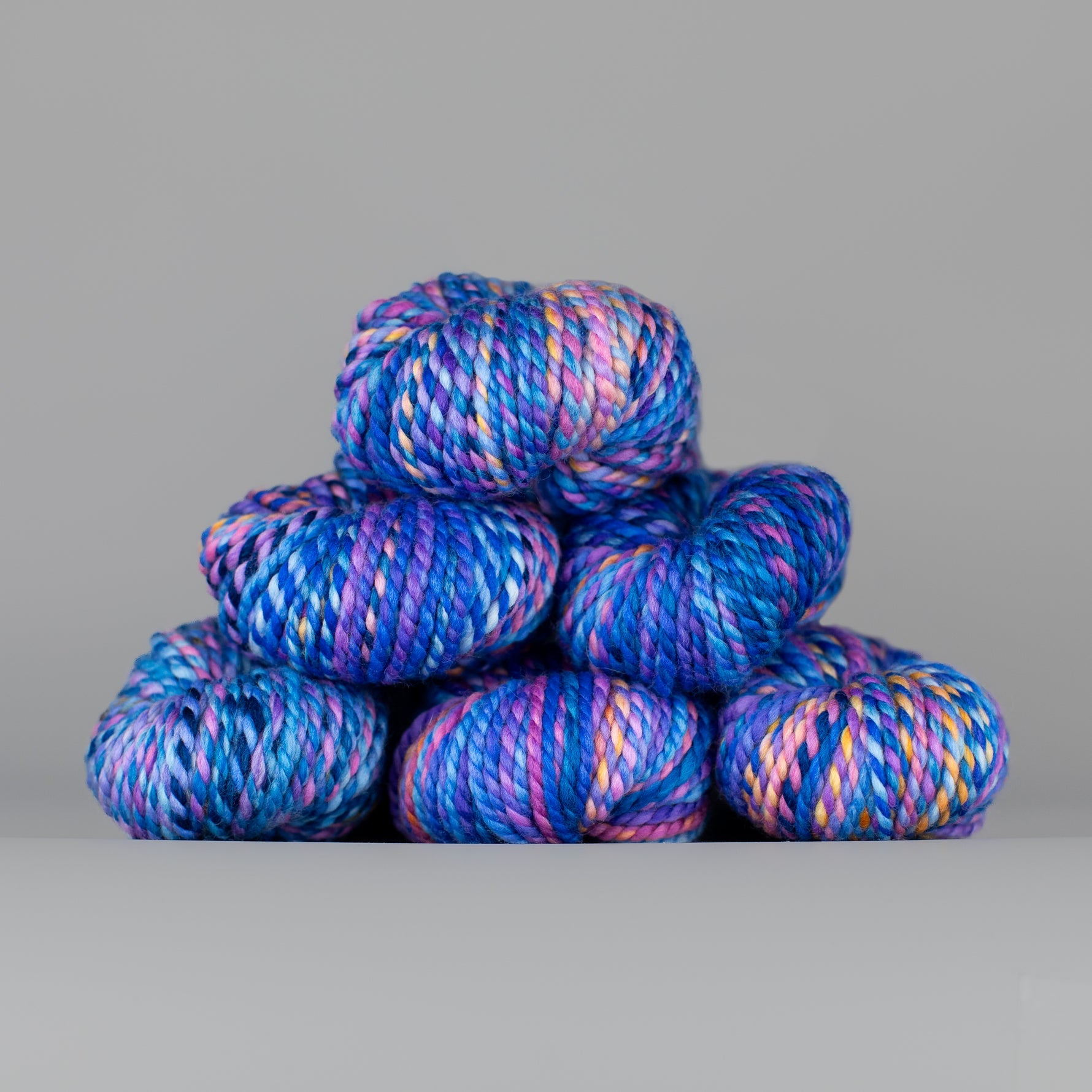 Skeins of Spincycle Plump Bulky weight yarn in blue, purple, pink, and orange color gradient