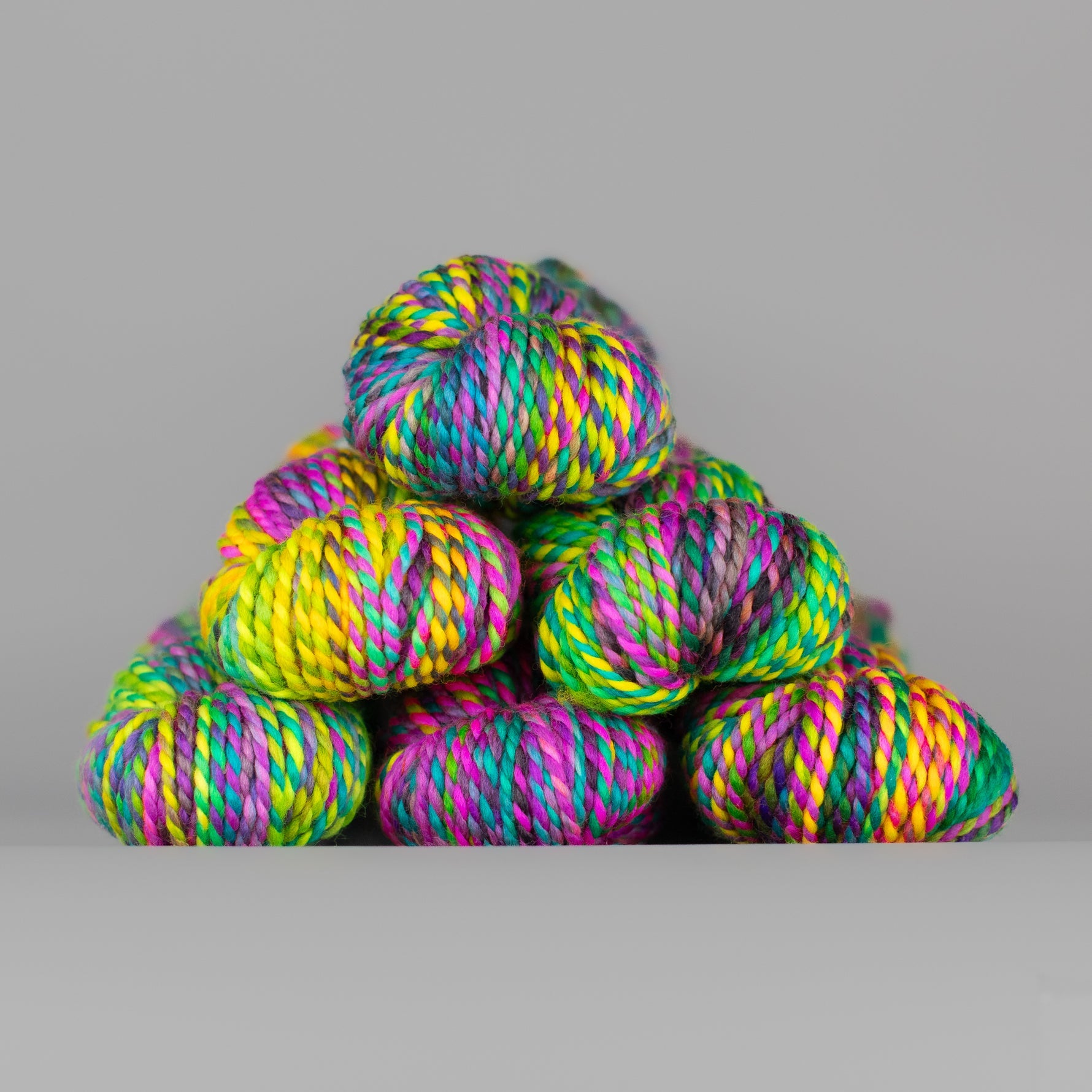 Skeins of Spincycle Plump Bulky weight yarn in yellow, aqua blue, purple, green, and pink color gradient