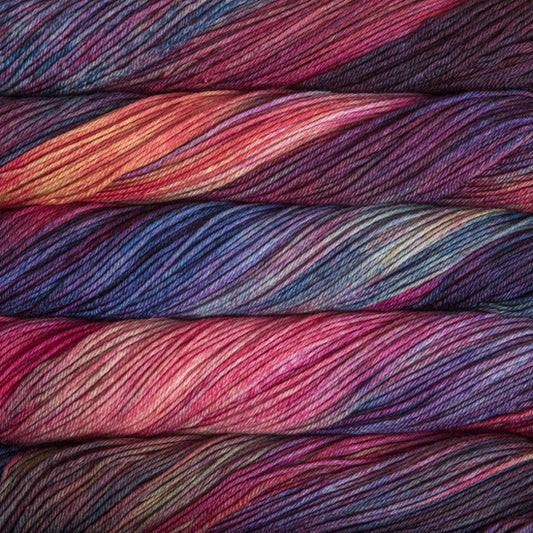 An image of skeins of Malabrigo Arroyo sport weight yarn in the color ‘Aniversario,’ in shades of blue, pink, and purple.