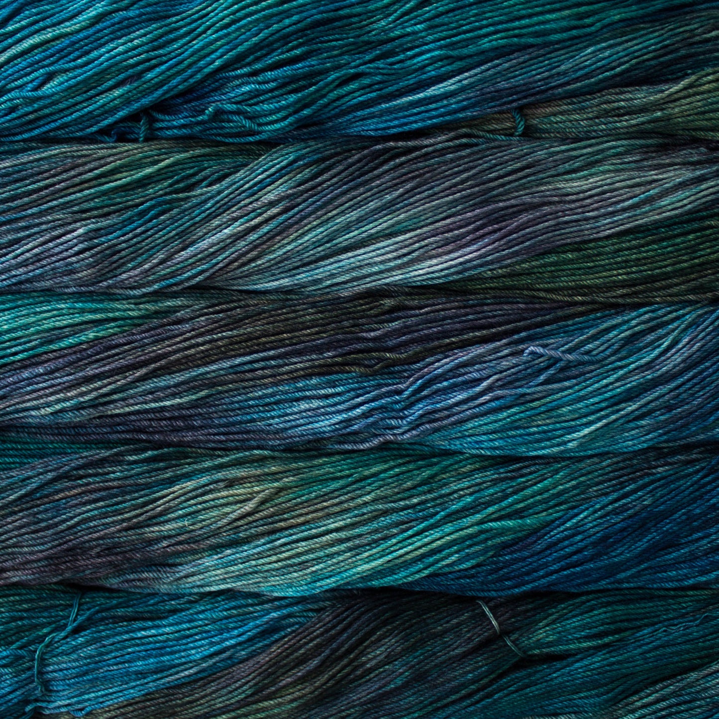 An image of skeins of Malabrigo Arroyo sport weight yarn in teal, green, and purple shades.