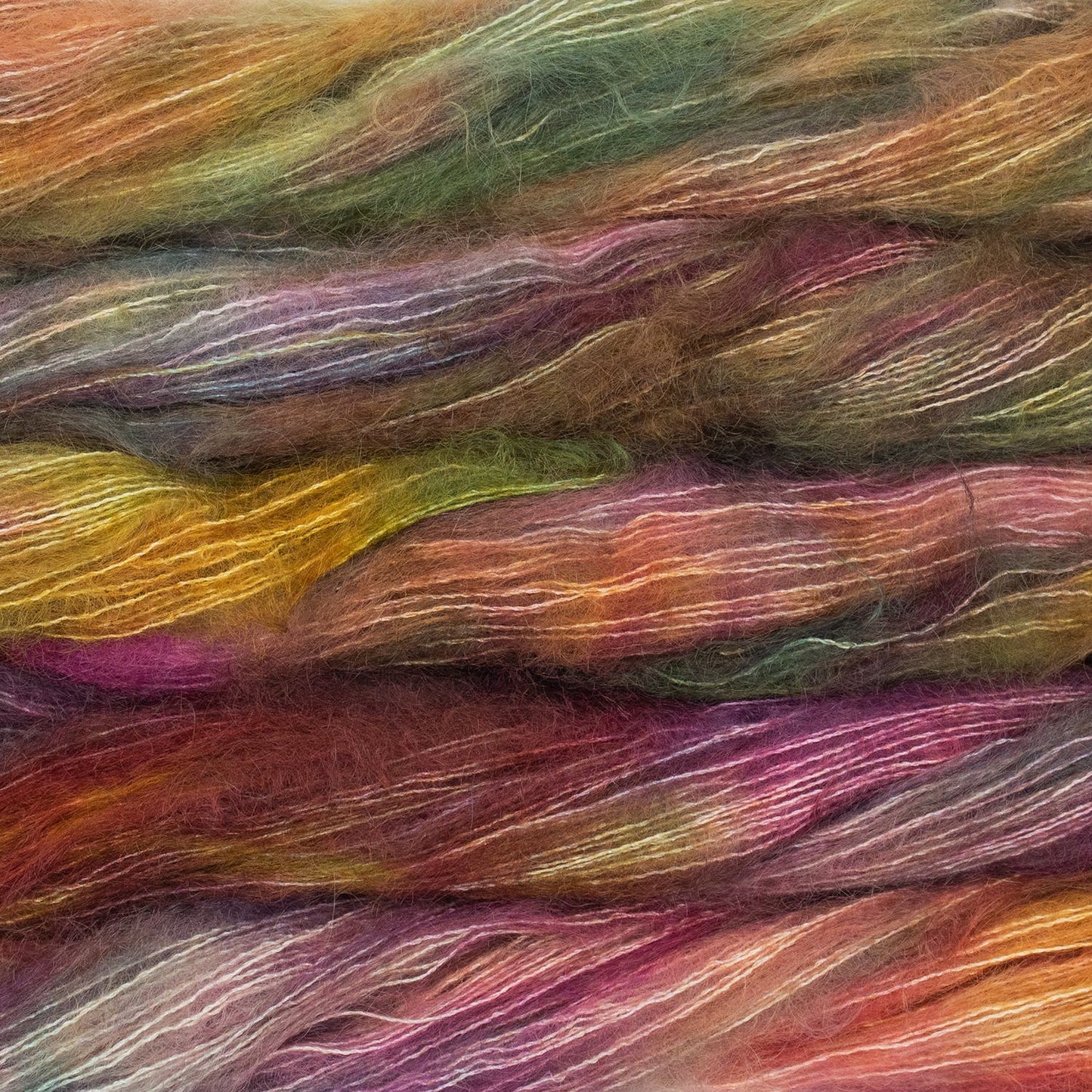 An image of multiple skeins of Malabrigo Mohair yarn in shades of yellow, magenta, and green.