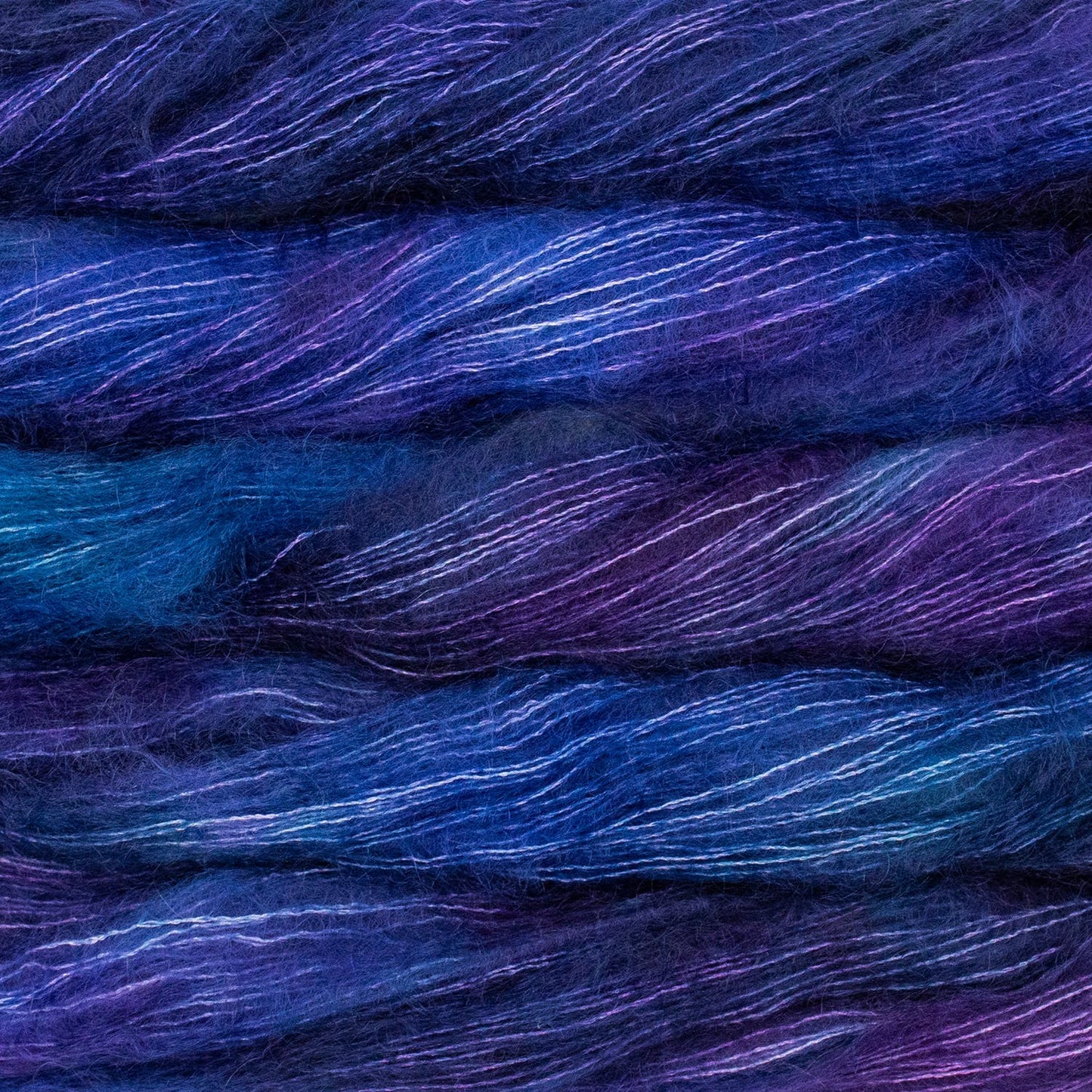 An image of multiple skeins of Malabrigo Mohair yarn in shades of electric blue and purple.