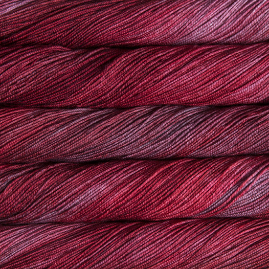 A close-up image of skeins of Malabrigo Sock yarn in shades of red and pink.