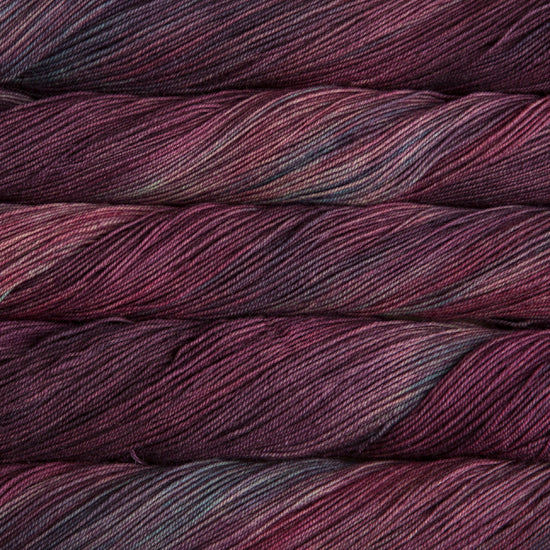 A close-up image of skeins of Malabrigo Sock yarn in deep purple and green shades.