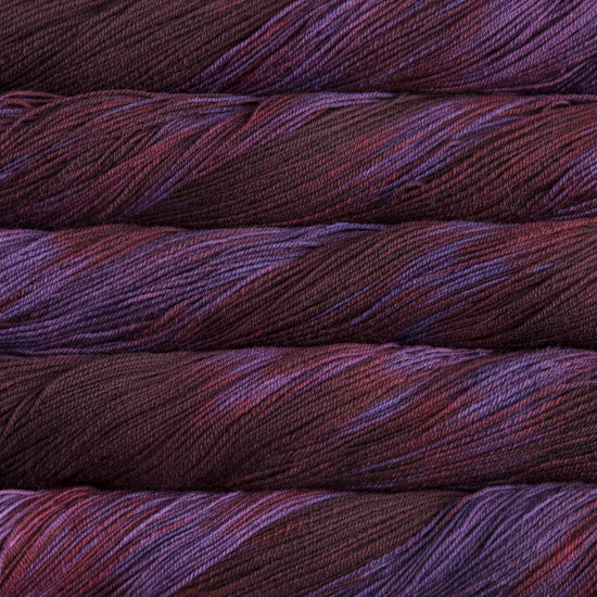 A close-up image of skeins of Malabrigo Sock yarn in deep red and purple colors.