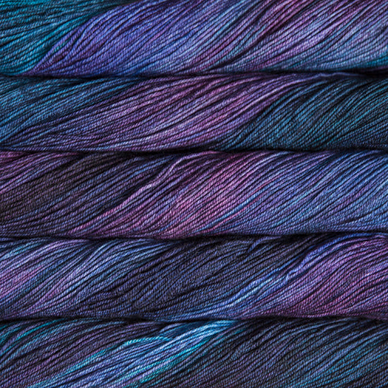 A close-up image of skeins of Malabrigo Sock yarn in dark blue and purple shades.