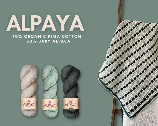 Alpaya yarn with a knitted blanket on a ladder against a green background