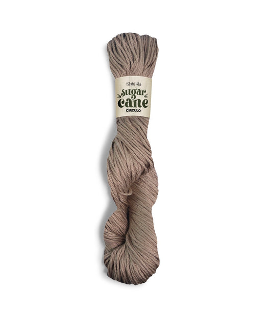 An image of a skein of Circulo DK weight yarn in a tan color with a ‘Sugar Cane’ label against a white background.