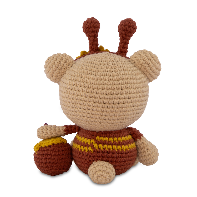 Crocheted teddy bear wearing a bee suit on a white background