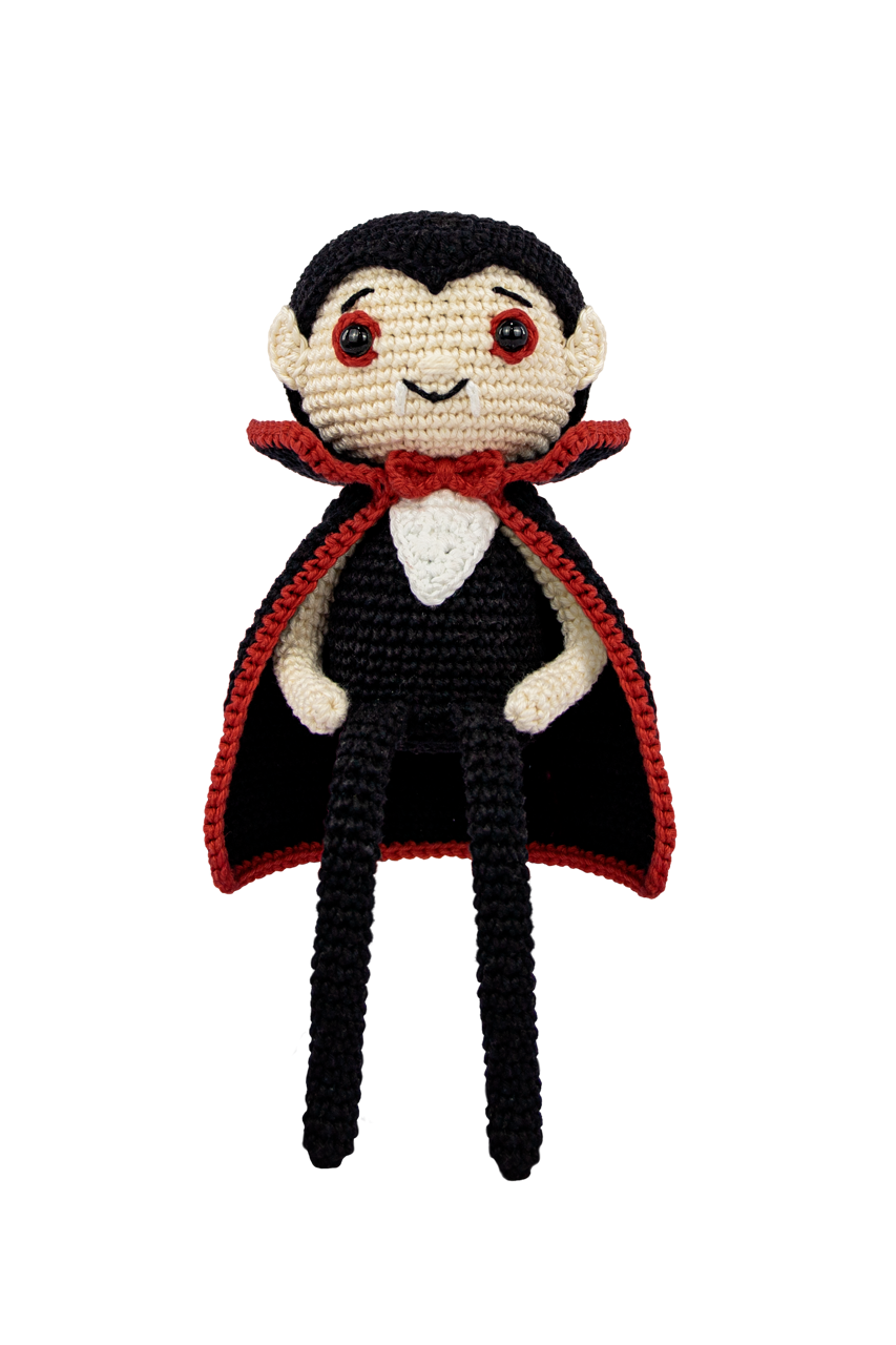 A crocheted vampire doll with black hair, a black suit, a red cape with a red inner lining, and a white shirt and collar, shown against a plain white background.