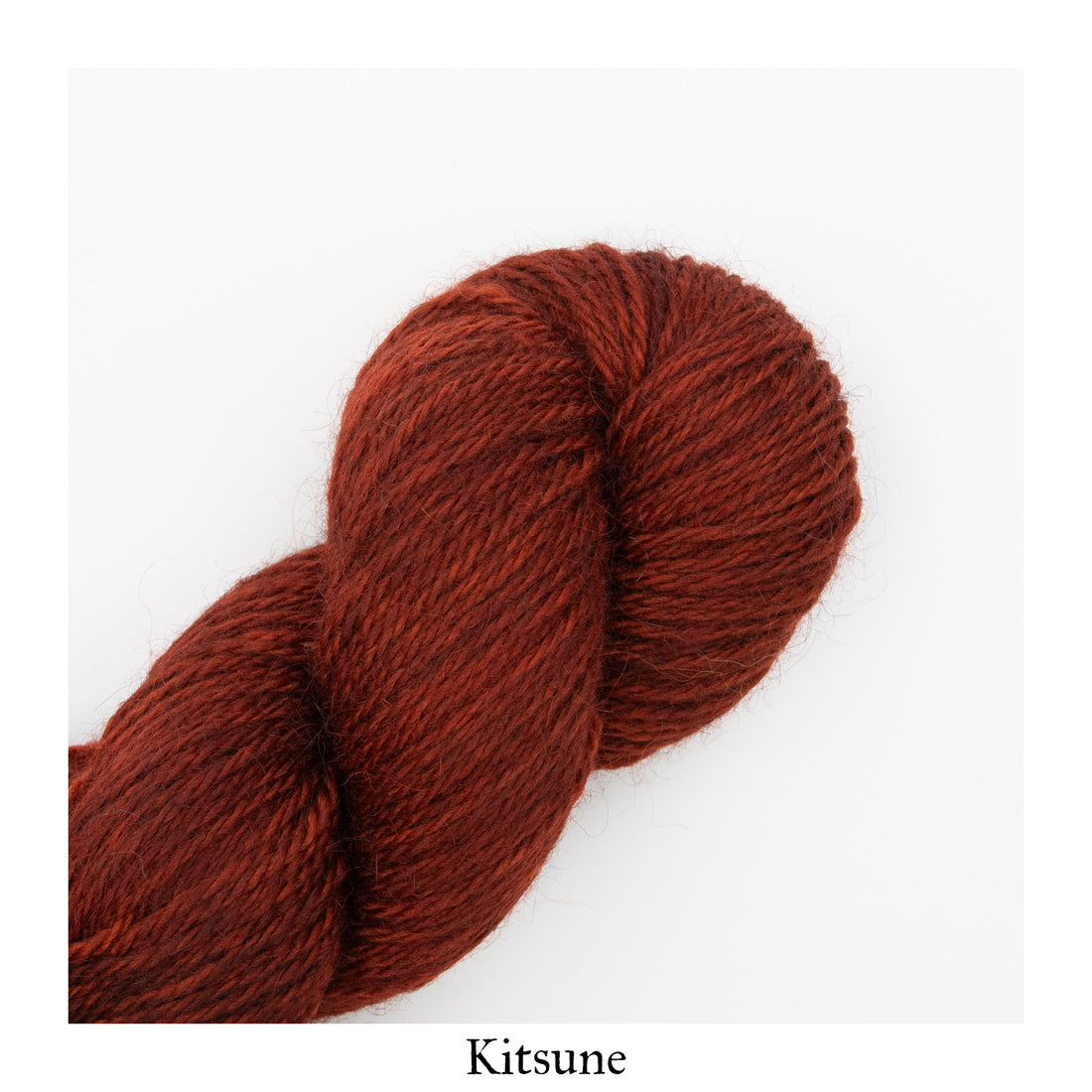An image of a skein of worsted weight yarn in a heathered rust orange color against a white background with the label ‘Kitsune’ at the bottom of the image.