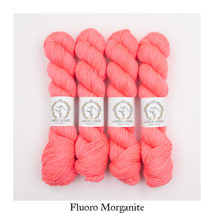 An image of four skeins of DK weight yarn in a neon pink color with white ‘La Bien Aimee’ labels against a white background.