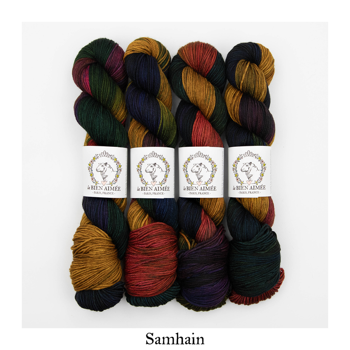 An image of four skeins of DK weight yarn dark shades of blue, green, orange, purple, and yellow with white ‘La Bien Aimee’ labels against a white background.