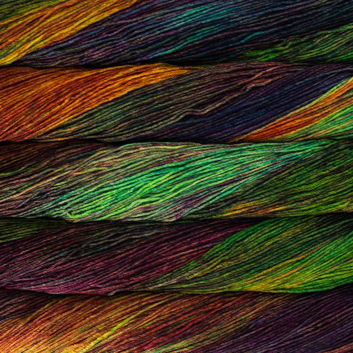 An image of skeins of Malabrigo Arroyo sport weight yarn in vibrant green, orange, red, and purple shades.