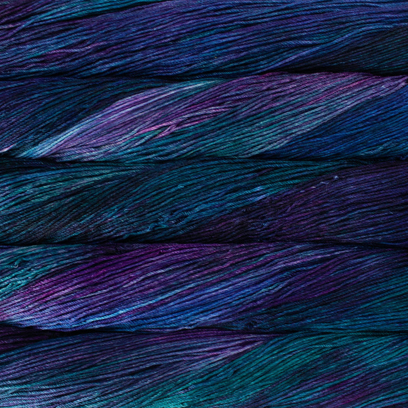 An image of skeins of Malabrigo Arroyo sport weight yarn in deep purple, blue, and teal shades.