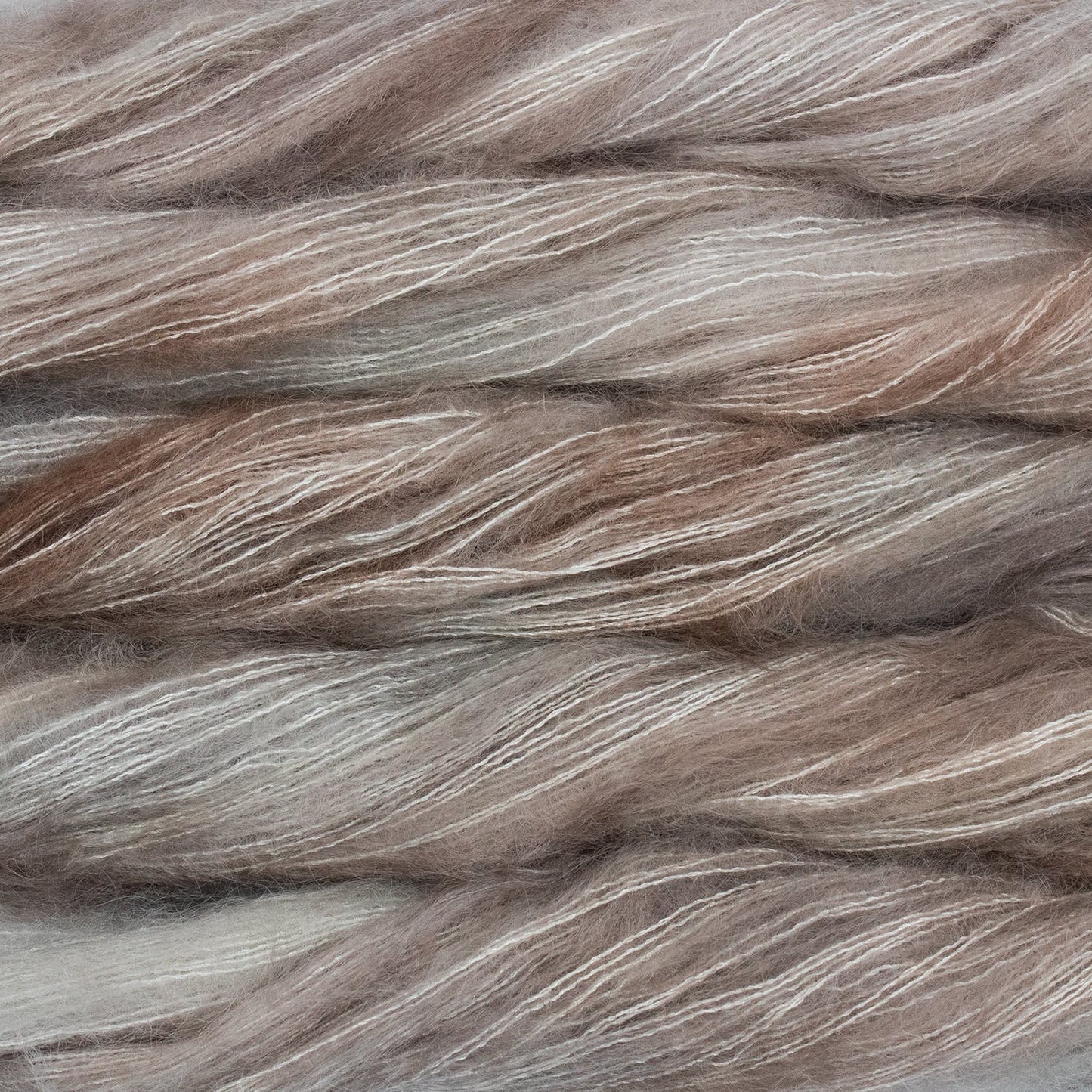 An image of multiple skeins of Malabrigo Mohair yarn in cream and light brown shades.
