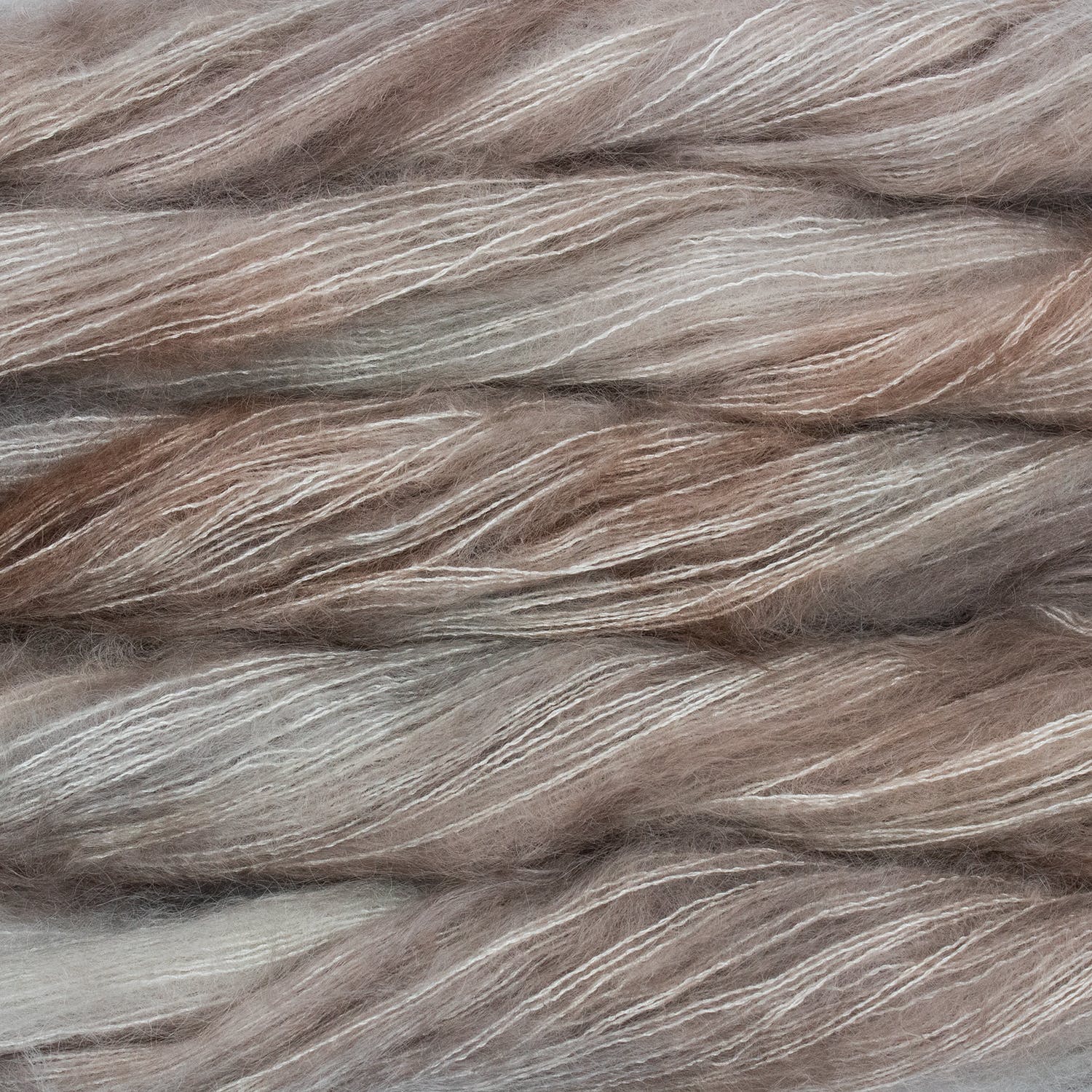 An image of multiple skeins of Malabrigo Mohair yarn in cream and light brown shades.