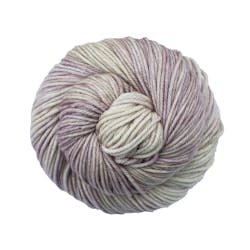 A close up of a skein of Malabrigo Rios worsted weight yarn in off white and pale purple colors