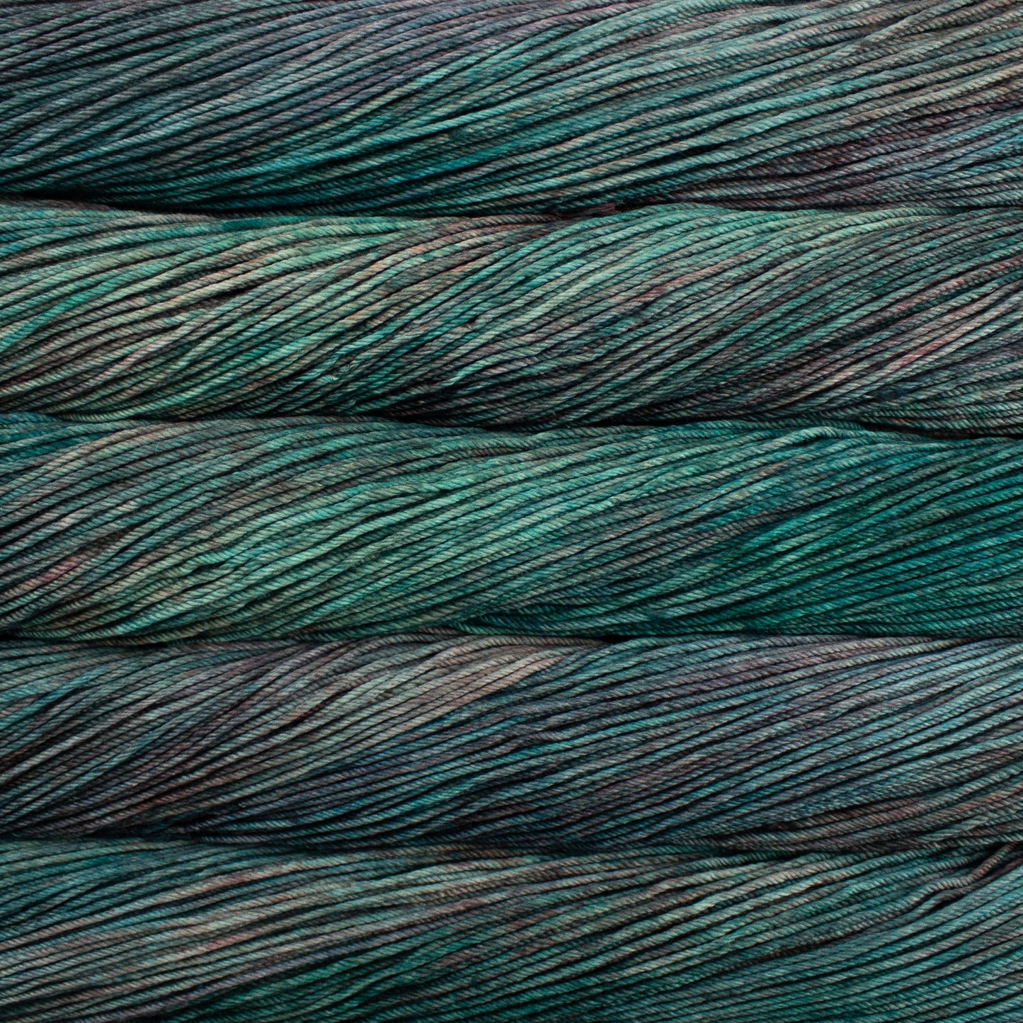A close up of skeins of Malabrigo Rios worsted weight yarn in deep green, teal, and brown colors