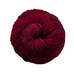 A close up of a skein of Malabrigo Rios worsted weight yarn in red and mauve colors