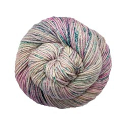 A close up of a skein of Malabrigo Rios worsted weight yarn in off white color with pink and teal speckled color