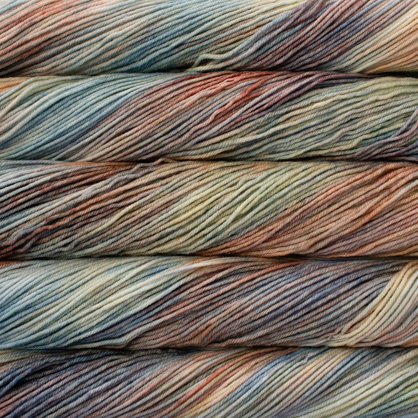 A close up of skeins of Malabrigo Rios worsted weight yarn in pale orange, blue, green, yellow, and purple colors.