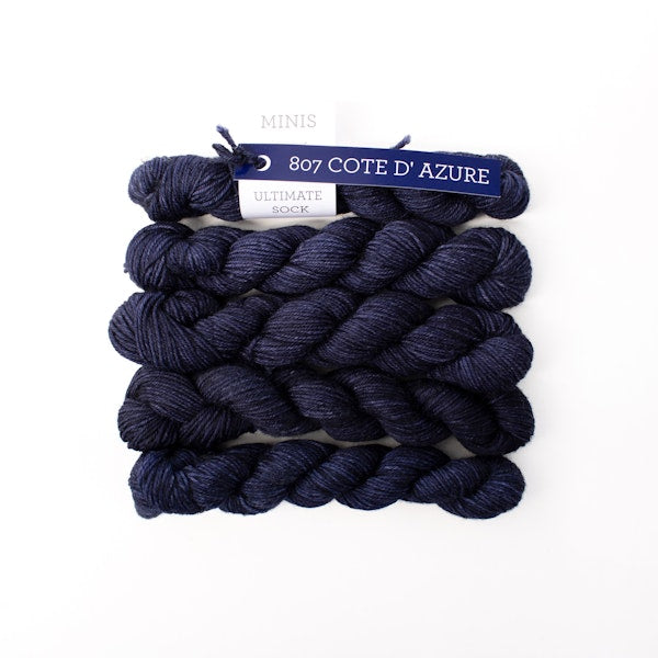 Multiple mini skeins of Malabrigo Ultimate Sock Cote D'Azure, dark blue kettle dyed sock yarn against a white background