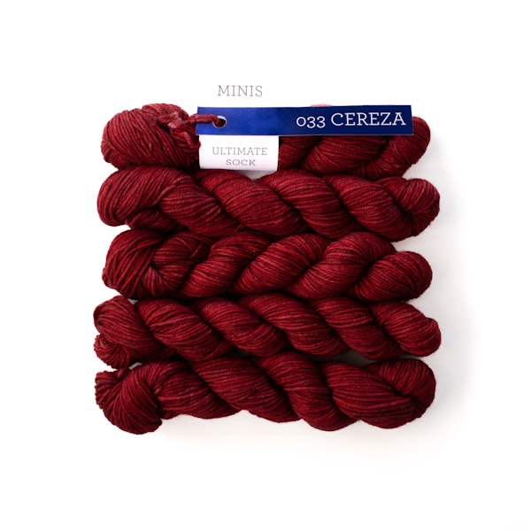 Multiple mini skeins of red sock yarn against a white background