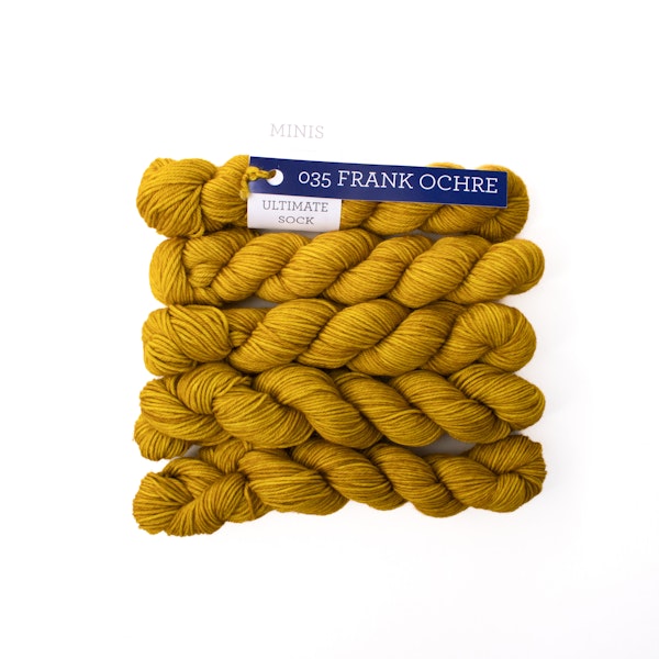 Multiple mini skeins of Malabrigo Ultimate Sock Frank Ochre, mustard yellow sock yarn against a white background