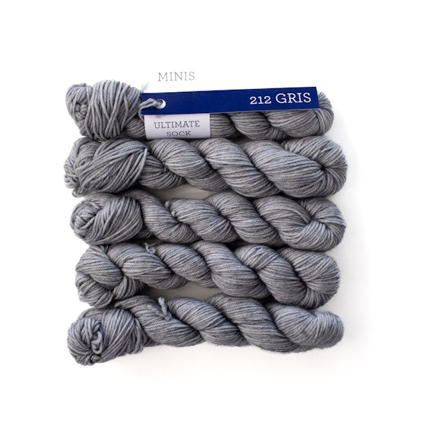 Multiple mini skeins of Malabrigo Ultimate Sock Gris, light gray kettle dyed sock yarn against a white background