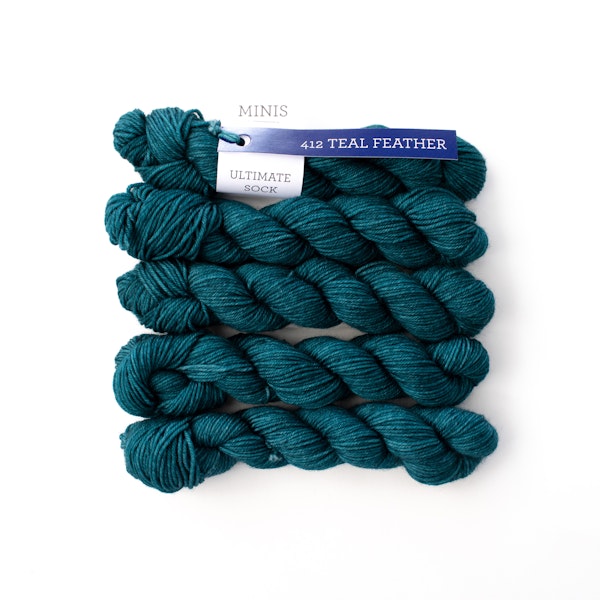 Multiple mini skeins of Malabrigo Ultimate Sock Teal Feather kettle dyed teal green blue sock yarn against a white background