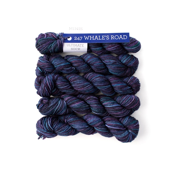 Multiple mini skeins of Malabrigo Ultimate Sock Whales Road,dark blue and purple sock yarn against a white background
