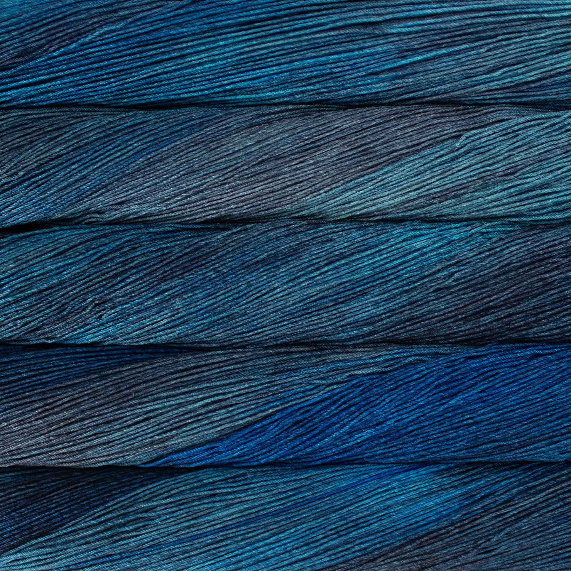A close up of a skein of Malabrigo Ultimate Sock fingering weight yarn in light and dark blue grey colors