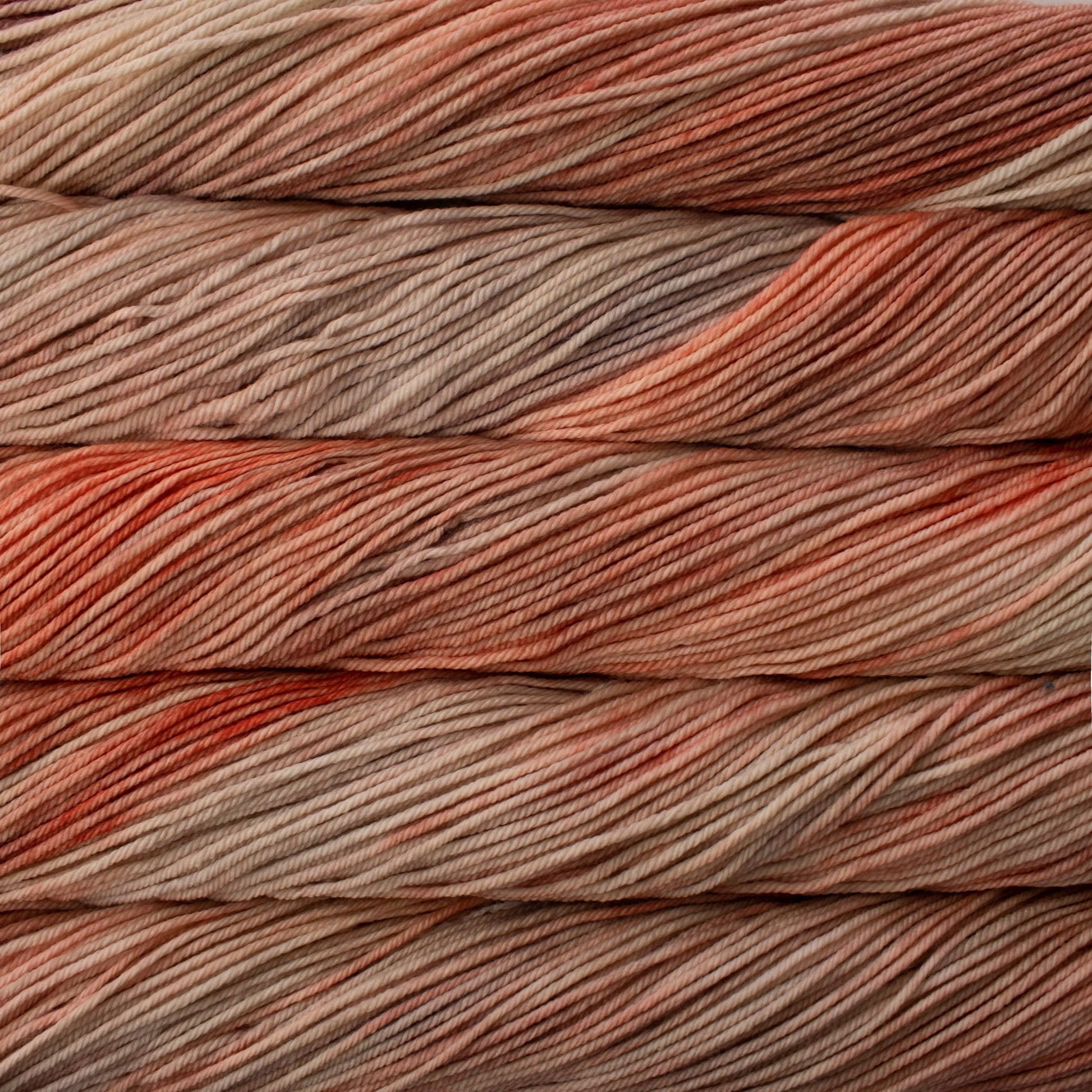 A close up of skeins of Malabrigo Rios worsted weight yarn in beige and light orange pink colors