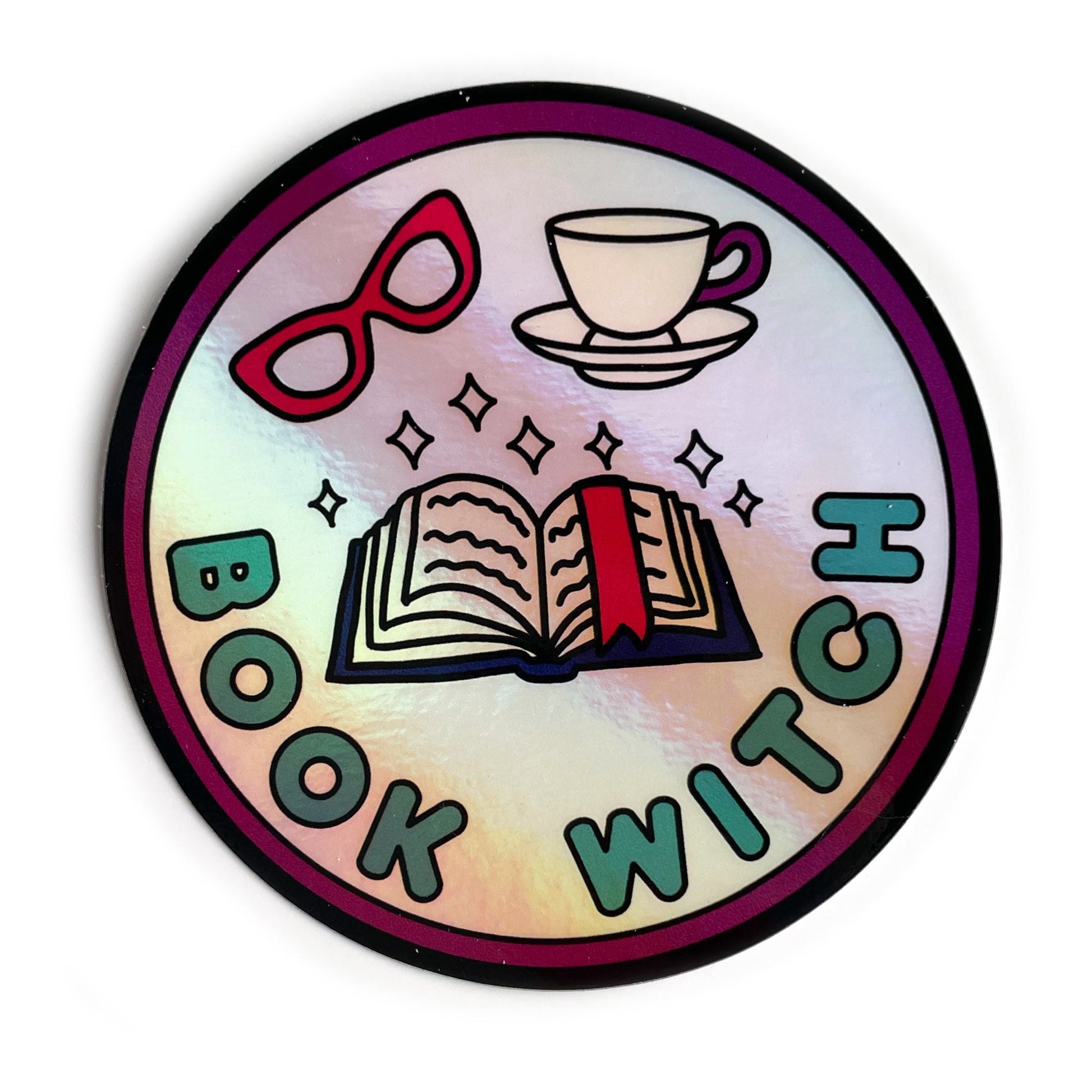 A circular holographic sticker. It has a maroon border with turquoise text that reads "Book Witch". There is an open book, sparkles, red glasses and a teacup above the words.