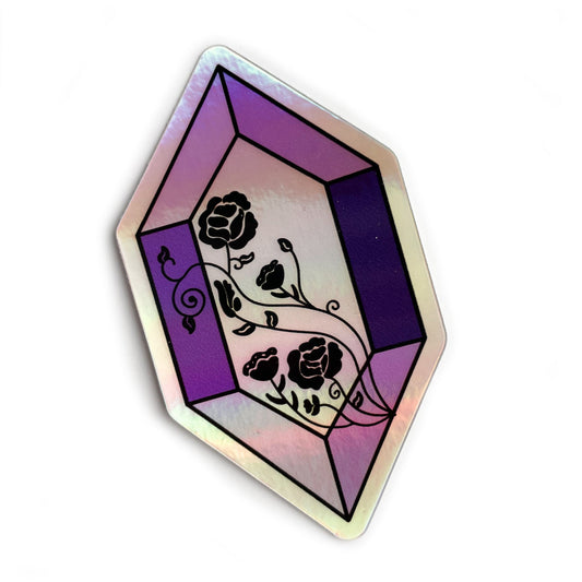 A holographic sticker in the shape of an elongated rectangle. It is various shades of purple and has roses in black line art across the face.