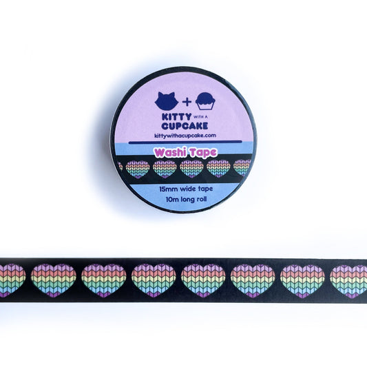 A roll of washi tape above a sample of that washi tape that has a black background with hearts with a pastel rainbow stockinette knit stitch pattern on them. 