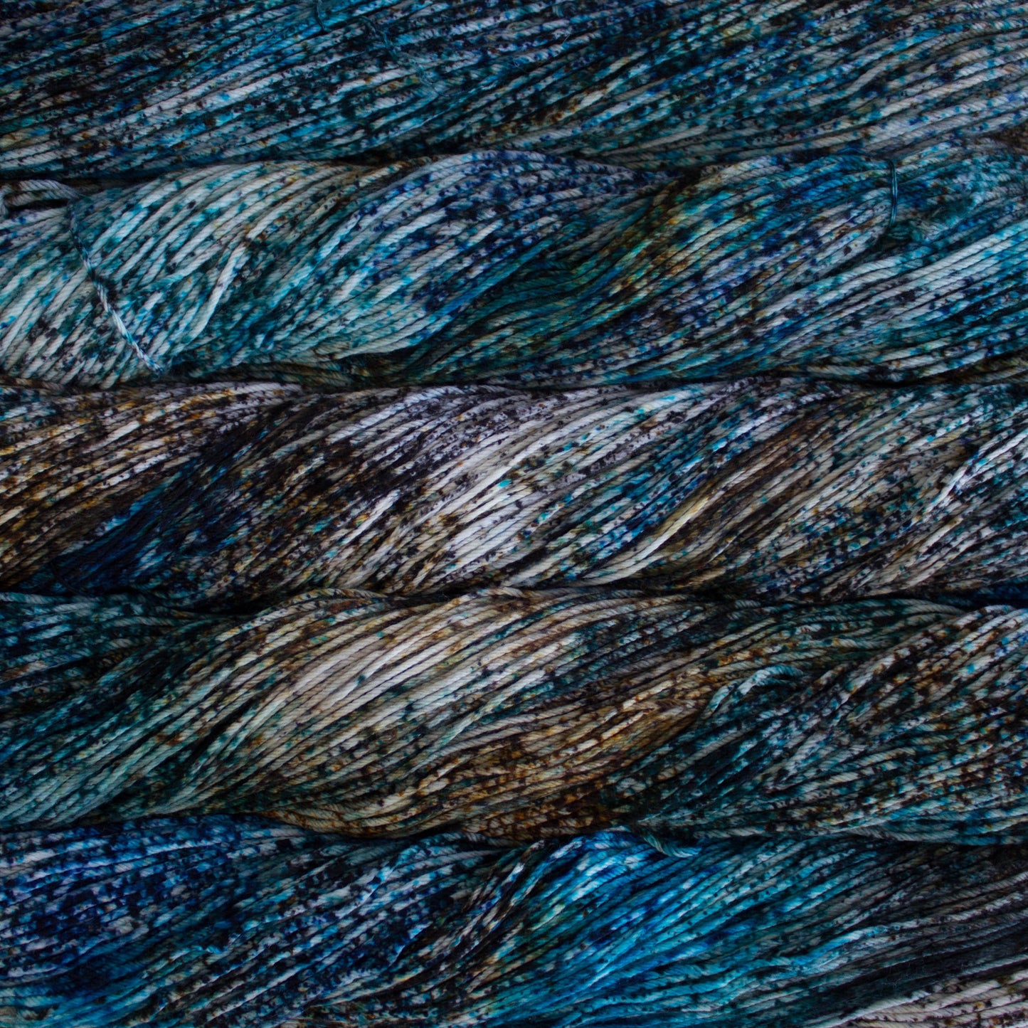 An image of skeins of Malabrigo Arroyo sport weight yarn in brown, cream, and pale blue shades, with speckles of navy blue.