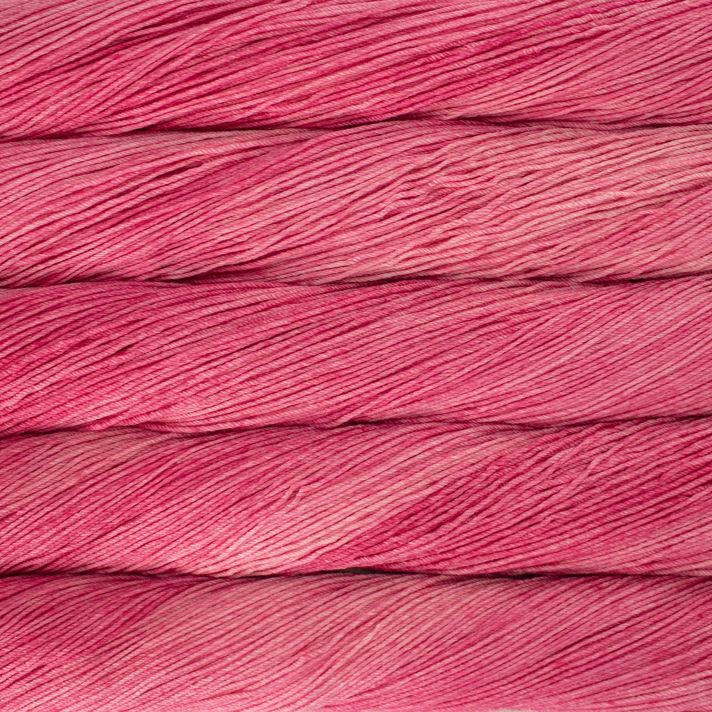 An image of skeins of Malabrigo Arroyo sport weight yarn in vibrant pink shades.