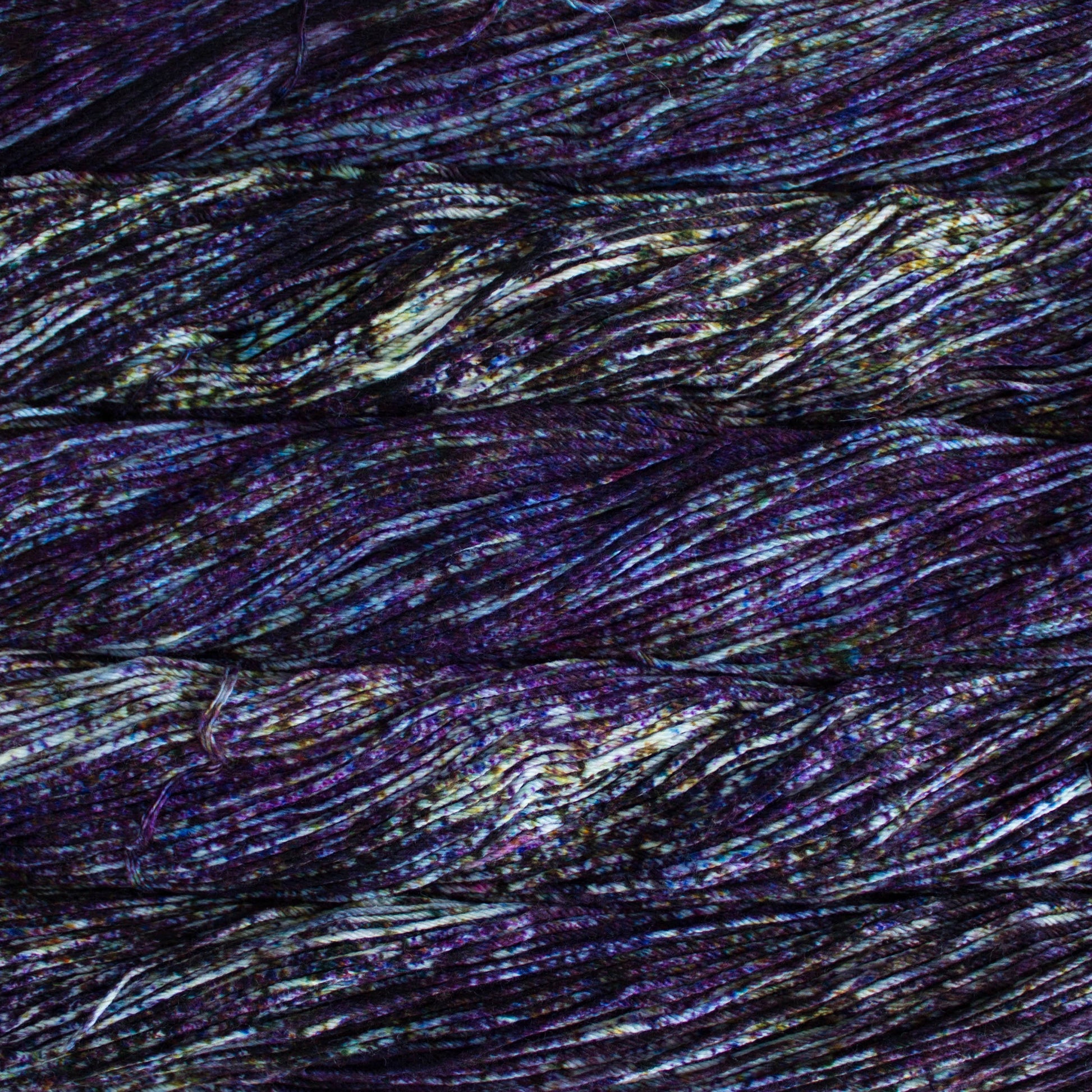 An image of skeins of Malabrigo Arroyo sport weight yarn in an off-white base with speckles of purple, blue, and orange.