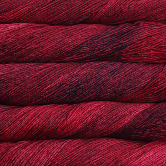 An image of skeins of Malabrigo Arroyo sport weight yarn in deep red shades.