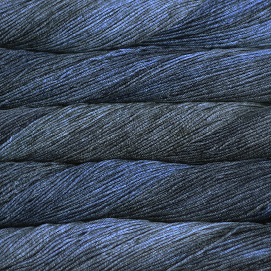 An image of skeins of Malabrigo Arroyo sport weight yarn in navy blue and charcoal shades.