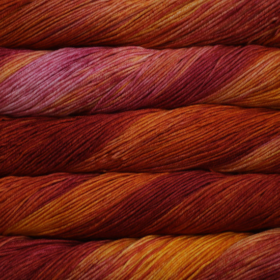 An image of skeins of Malabrigo Arroyo sport weight yarn in dark, orange, and light pink shades.